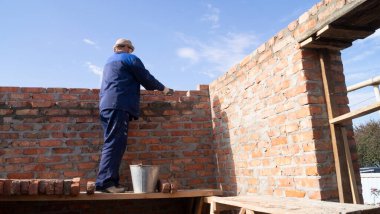 Duvarcı iskeleye tuğla döşemiş.