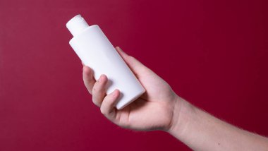 Elinde losyon şişesi tutan bir adam.