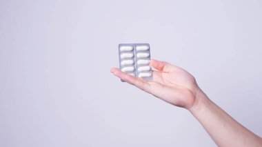 Bir adamın elinde bir paket hap var.