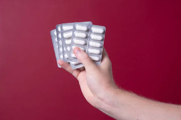 a man\'s hand holds a package of pills