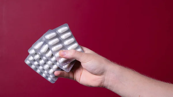 a man\'s hand holds a package of pills