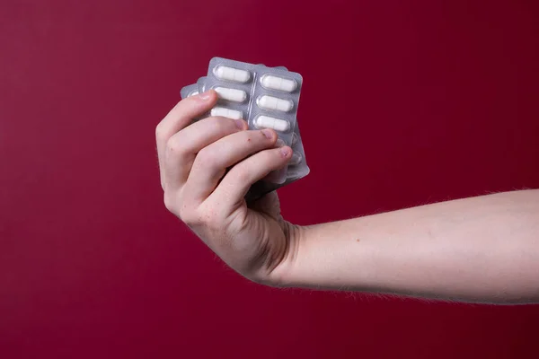 a man\'s hand holds a package of pills