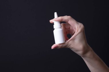 Kadın eli burun spreyi tutuyor.