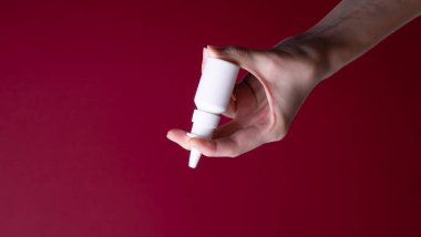 Kadın eli burun spreyi tutuyor.