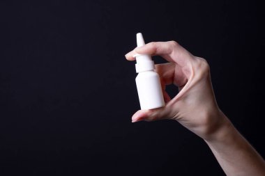 Kadın eli burun spreyi tutuyor.