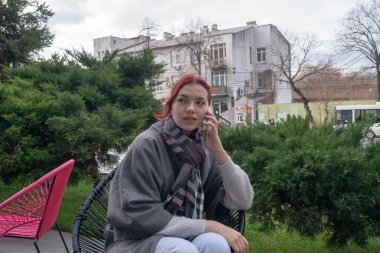 Terasta telefonlu bir kadın var.