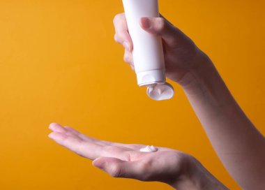 Bir kadın eline krem ya da losyon sürer.