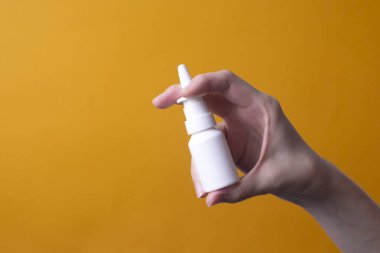 Kadın eli burun spreyi tutuyor.