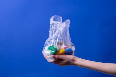 Bir kadının eli, geri dönüşüm için plastik kapaklı bir çanta tutar.