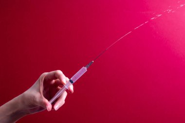 Kadın eli tıbbi şırınga tutuyor.