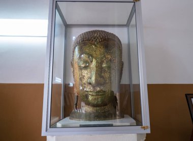 Cam bir dolapta tutulan Buda heykelinin başı, eski bir his verir..