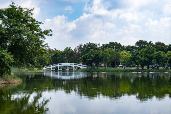 Ağaçlarla çevrili küçük bir nehrin üzerinde bir köprü ve arkasında da gökyüzü var..