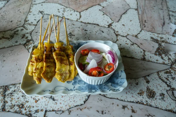 Şiş üzerinde ızgara domuz eti, sebzeli bir tabakta, mermer bir masada..