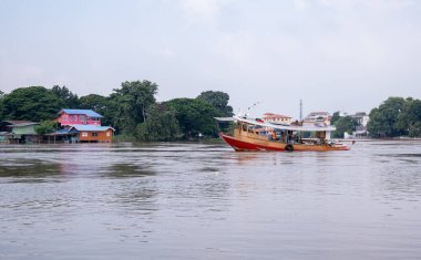 Tekne nehirde yüzüyordu, kıyıda bir ev vardı..