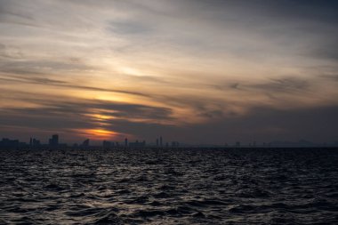 Sabahları deniz ve gökyüzü puslu, pirinç tarlasına bakan şehir..