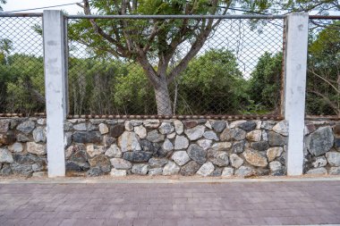 Büyük bir duvar çiti, bir sürü granitle süslenmiş, ve işlenmiş demirle güçlendirilmiş..