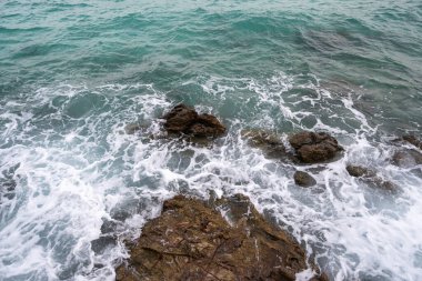 Deniz dalgaları kayalara çarptı, sahil şiddetli bir şekilde köpüğe sebep oldu..