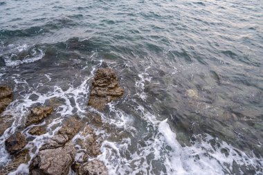 Deniz kenarında her zaman dalgalar tarafından ısırılan bir sürü kaya vardır..