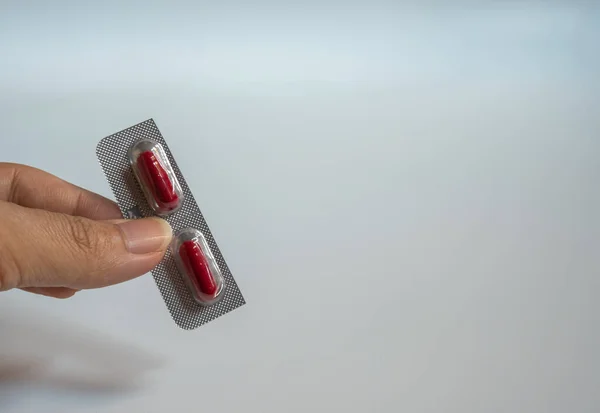Duas Cápsulas Pílula Vermelha Sendo Realizada Com Dedos Fundo Branco — Fotografia de Stock