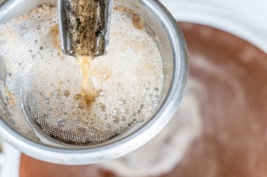 Eski moda dökme demir elmanın nasıl kullanılacağını gösteriyorum. Eski bir meyve sıkacağıyla taze elma suyu hazırlıyorum. Seçici odaklanma, elma suyu yakından akıyor, arka planda elma suyu olan fıçı.