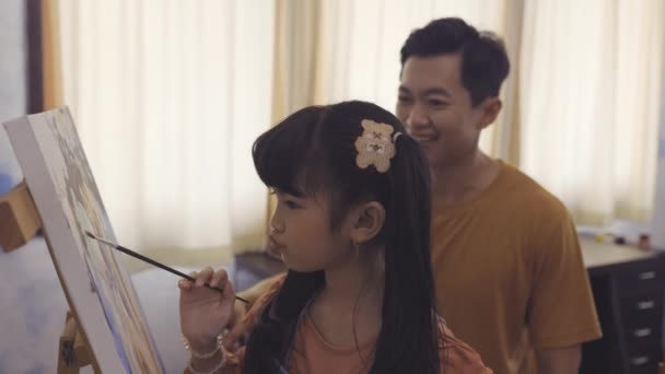 Οικογένεια του νεαρού πατέρα που μαθαίνει στην κόρη του να ζωγραφίζει μαζί. Γονική μέριμνα και πατρότητα. — Αρχείο Βίντεο