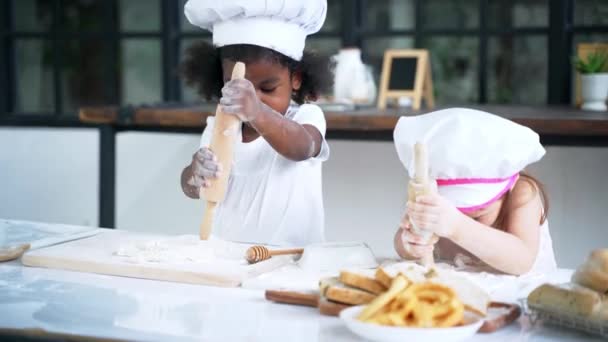 Petite fille cuire des biscuits dans la cuisine tout en copiant et en regardant enfant dans la classe à l'école — Video