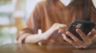 Kafede akıllı telefon kullanan maskeli bir kadın.