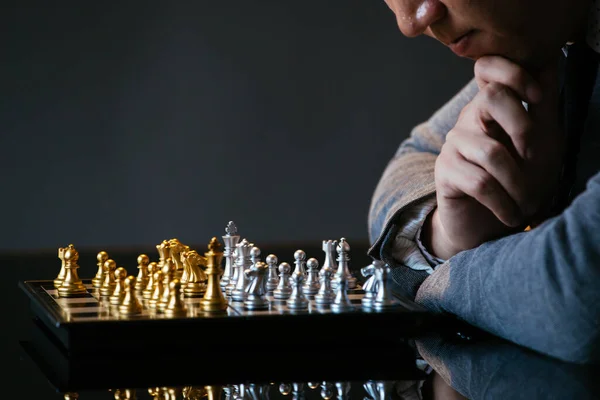 灰色の背景にガラスのテーブルでチェスをプレイしながらあごをこすり 次の動きを考える男のクロップドショット — ストック写真