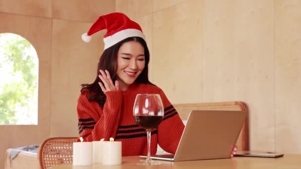 아시아의 여성이 스웨터를 모자를 방에서 와인과 양초를 테이블에 흔들고 노트북을 — 비디오