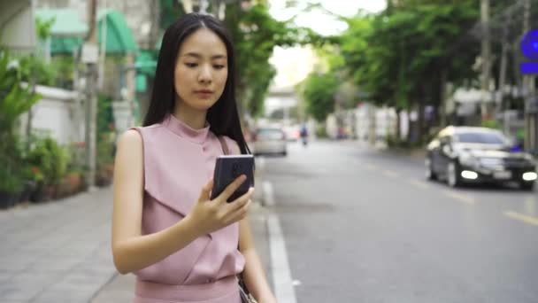 Yol Kenarındaki Mutlu Asyalı Kadını Elinde Akıllı Telefonla Taksiyi Iletişimi — Stok video