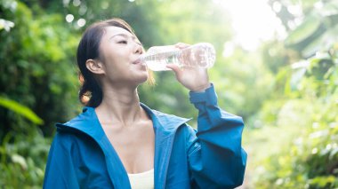 Genç dişi kaşif orman dağ yolunda yürürken su içiyor. Asyalı kadın susuz kalıyor..