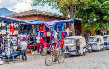 Antigua, Guatemala - 25 Eylül 2021 - Mercado Central önünde bir bisikletçi ve tuk-tuk taksilerinin sokak fotoğrafları
