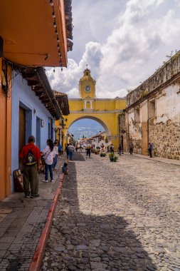 Antigua, Guatemala - 26 Eylül 2021 - bulutlu bir günde Santa Catarina Kemeri 'ndeki turistlerin dikey sokak görüntüsü