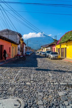 Antigua, Guatemala - 27 Eylül 2021 - arka planda Agua Volkanı olan koloni renkli evlerin dikey sokak fotoğrafçılığı