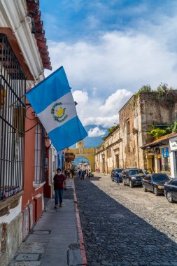 Antigua, Guatemala - 26 Eylül 2021 - Guatemala bayrağı ve Santa Catalina Kemeri 'ndeki turistlerin dikey sokak fotoğrafları