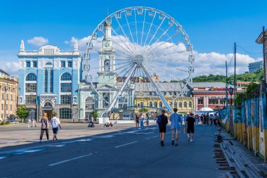 Podil, Kyiv, Ukrayna - 16 Haziran 2021 - Dönme dolap ve geleneksel mimari ile Podil Mahallesi 'nin ana meydanındaki insanlar