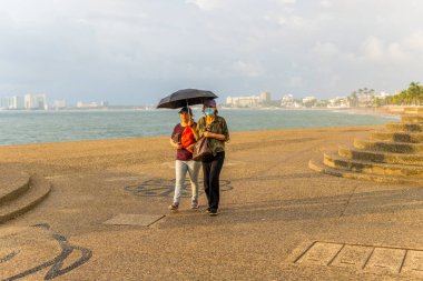 Puerto Vallarta, Meksika - 12 Eylül 2021 - İnsanlar yağmurlu bir günde Pasifik gezinti alanında yürüyorlar.