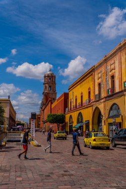 Queretaro, Meksika - 7 Eylül 2021 - Templo de San Francisco Kilisesi önündeki meydanda insanların dikey sokak fotoğrafçılığı