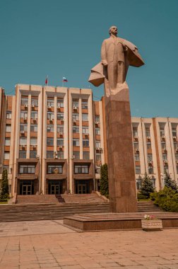 Tiraspol, Transnistria - 26 Haziran 2021 - Pridnestrovia Cumhuriyeti Yüksek Konseyi (Parlamentosu) önündeki bir Lenin heykelinin günbatımında dikey görüntüsü