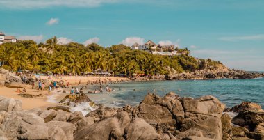 Puerto Escondido, Meksika - 14 Kasım 2021 - Puerto Escondido, Oaxaca 'daki Playa Manzanillo plajındaki kayaların panoramik günbatımı manzarası