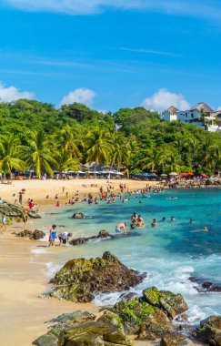 Puerto Escondido, Meksika - 14 Kasım 2021 - Playa Manzanillo 'da yüzen ve güneşlenen turistlerin dikey çekimi