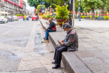 Puebla, Meksika - 28 Ağustos 2021 - Zocalo 'da bir sokakta oturan Meksikalı adamın gizli sokak fotoğrafı