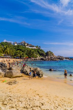 Puerto Escondido, Meksika - 14 Kasım 2021 - Playa Manzanillo 'da yüzen ve güneşlenen turistlerin dikey çekimleri
