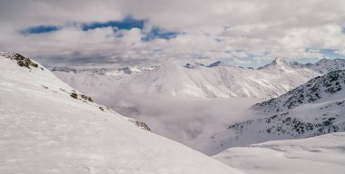 Amazing alpine panorama view in Livigno, Italy with clouds below snowy peaks