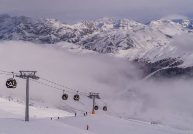 Livigno, Italy - December 28, 2021 - skiers and gondolas on a moody day