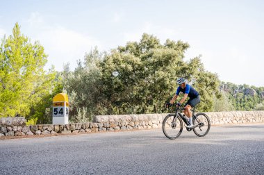Siyah bir bisikletin üstünde bisiklet eğitimi yapan bir sporcu. Bisikletçi geriye bakıyor. Kopyalama alanı olan resim