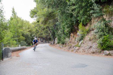 Bisikletçi yüksek hızla bir dağ yolunda viraj alıyor.