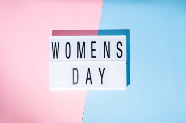 Kadınlar Günü, 8 Mart, ışık kutusunda. Pembe ve mavi arka planlı feminizm kavramının en üst görüntüsü