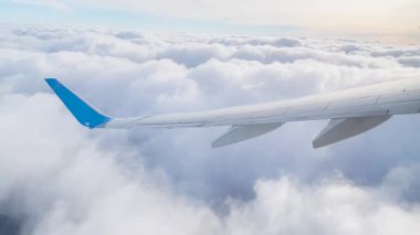 Bulutların üzerinde uçan bir uçağın kanadı. Gökyüzüne uçağın penceresinden bakar, seyahat etmek için hava taşımacılığını kullanır.