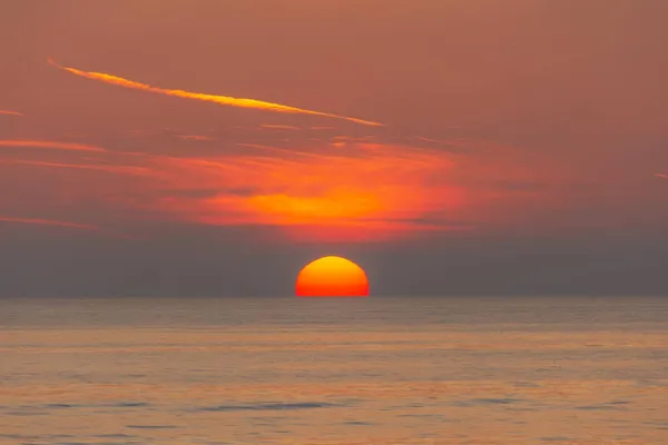 太陽の円盤は海の地平線に沈む — ストック写真